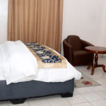large well lit room equiped with king sized bed, art works, sitting area, and a study desk.