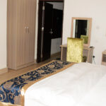 well lit bedroom equipped with a double bed, a study table, and flat screen tv